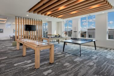lobby shot with open windows on a sunny day with shuffleboard, ping pong table, television and pool table to show amenities
