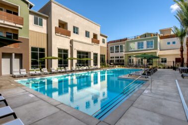 Poolside view of The Lark at Copper River Apartments with green umbrellas and tanning chairs