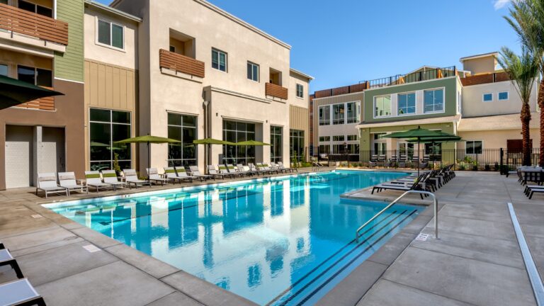 Poolside view of The Lark at Copper River Apartments with green umbrellas and tanning chairs