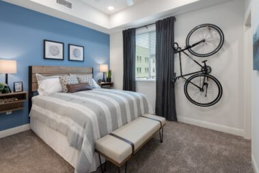 apartment bedroom with bicycle on the wall, blue painted accent wall and king mattress
