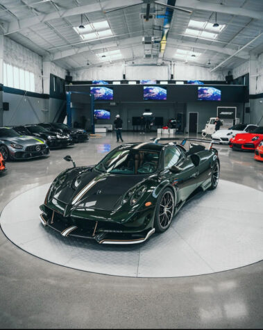 Interior view of a spacious custom metal warehouse constructed by Barken, featuring a green Pagani sports car on a central display platform under high ceilings and bright skylights.