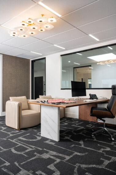 Executive office interior featuring a sleek wooden desk, marble-accented table, and modern lighting fixtures, showcasing high-end commercial tenant improvements by Barken.