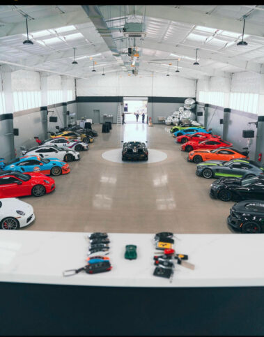 Wide elevated shot of a massive custom car storage warehouse built by Barken, demonstrating the vast floor plan and clear-span structural design capable of housing dozens of luxury vehicles.