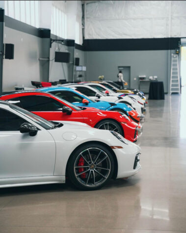 Close-up of a lineup of colorful Porsche sports cars safely stored inside a Barken-built commercial steel warehouse, showcasing the pristine concrete flooring and climate-controlled environment.